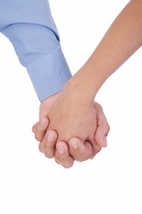 Closeup Of Young Affectionate Couple Holding Hands Over White Ba by David Castillo Dominici